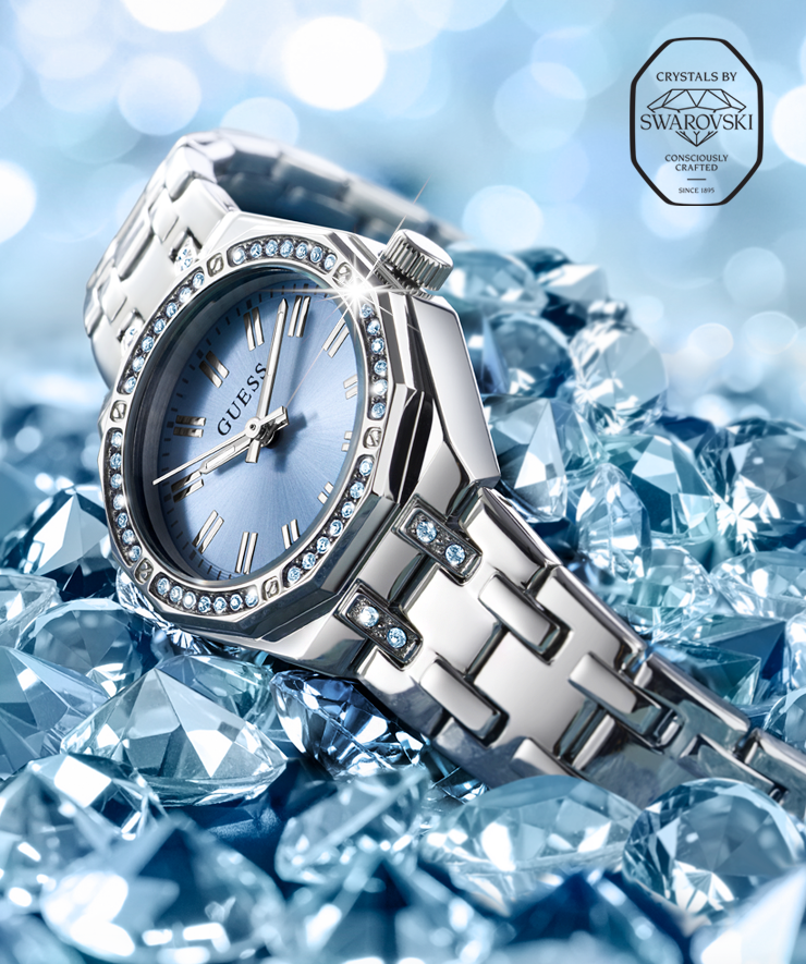 Silver watch with gemstones on a blue crystal background, featuring Swarovski crystals and logo in upper right.