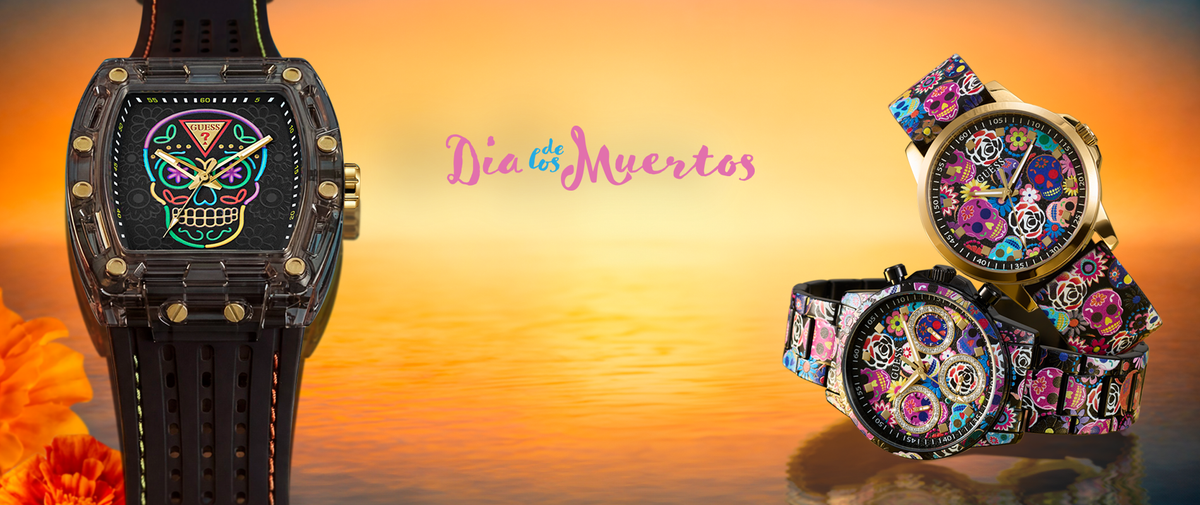 Three fashion watches with colorful floral and sugar-skull dial designs are displayed against a warm sunset background with the text 'Dia de los Muertos'.