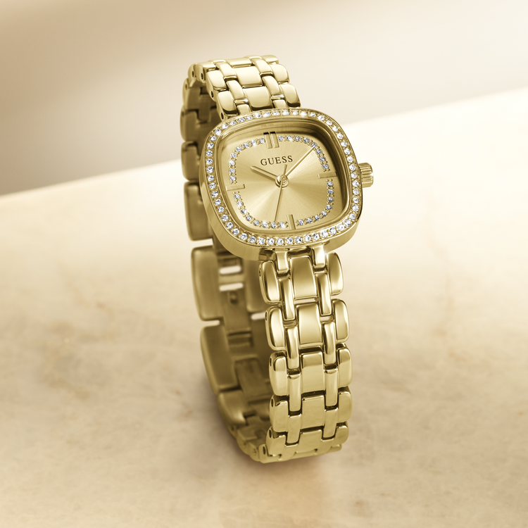 Gold watch with diamond-studded face on a beige surface