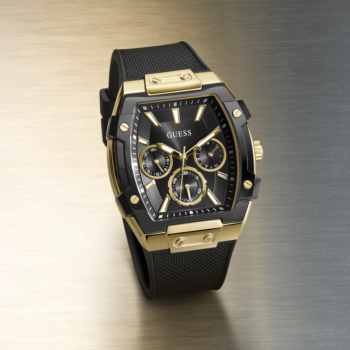 Gold and black watch with 'GUESS' branding on a gradient background