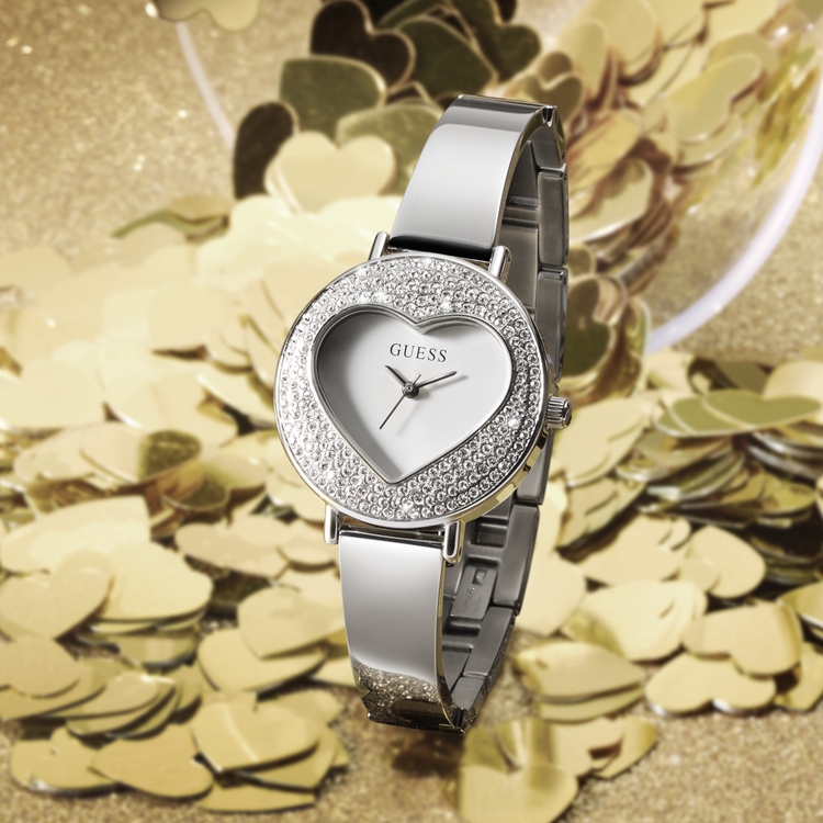Silver GUESS heart shaped watch on glitter gold background