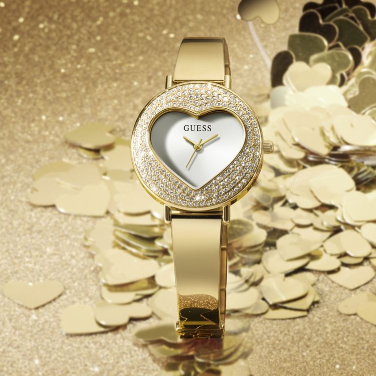 Gold Guess watch with heart-shaped face on a glittery gold background