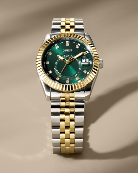 Two-tone watch with green face and gold accents on a beige background