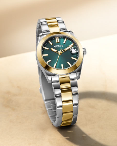 Two-tone Guess watch with green dial on a beige background