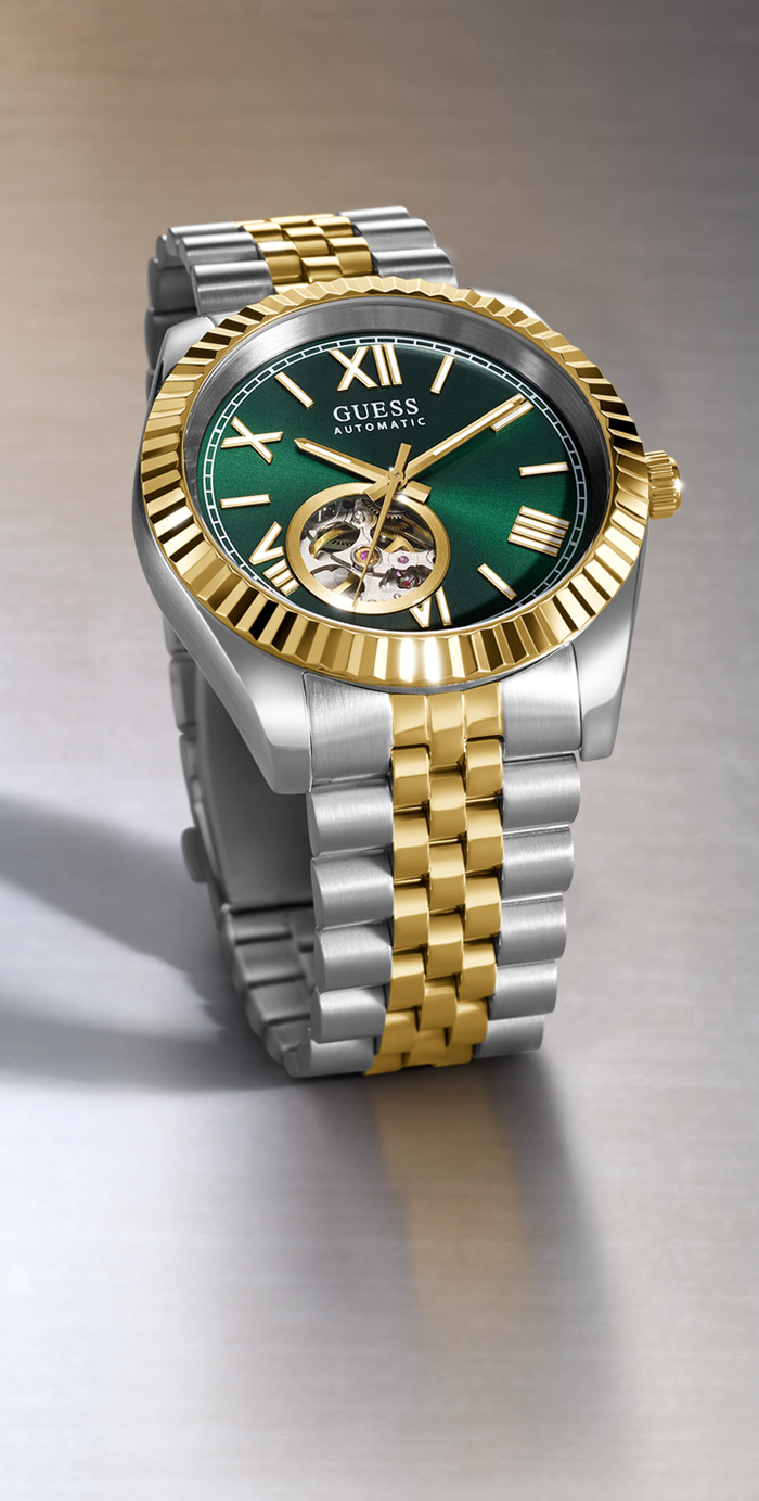 GUESS watch with green face, gold and silver band on gray background