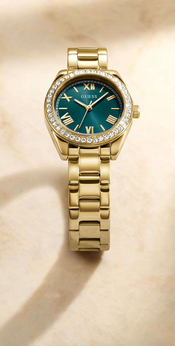 Gold watch with a green dial on a beige background