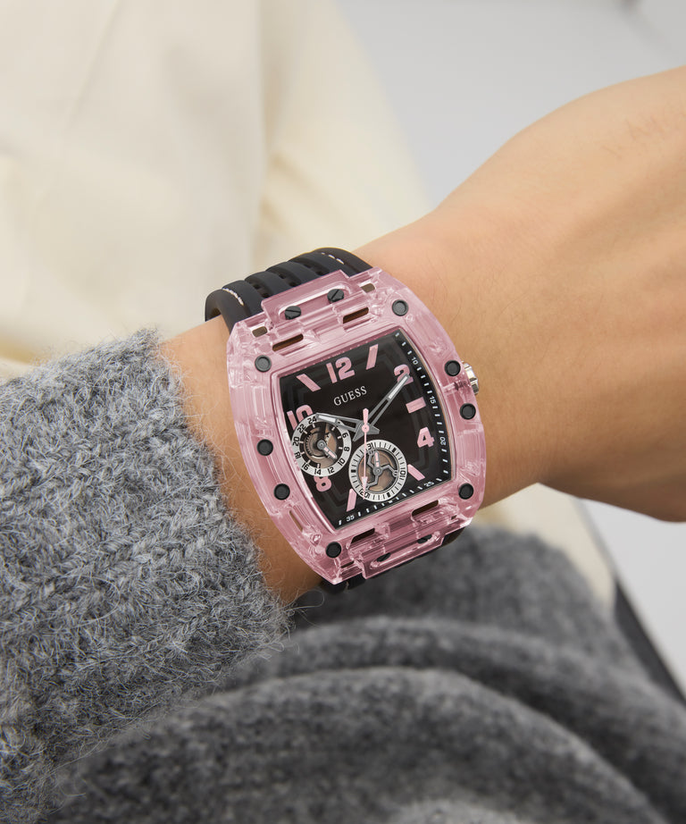 GUESS Mens Sporting Pink Multi-function Watch on a wrist with a blurred background