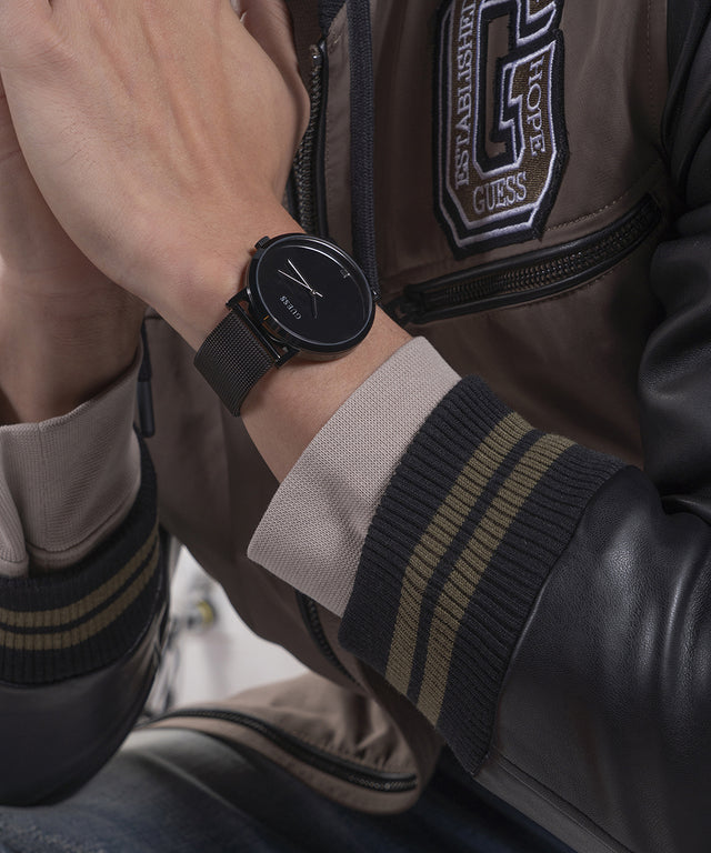 Person wearing a black watch with a jacket featuring a visible brand logo.