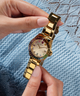 GW0475L3 GUESS Ladies Gold Tone Date Watch lifestyle hand holding watch