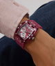 Close-up of a wrist wearing a red GUESS Mens Red Analog Watch with a detailed face.