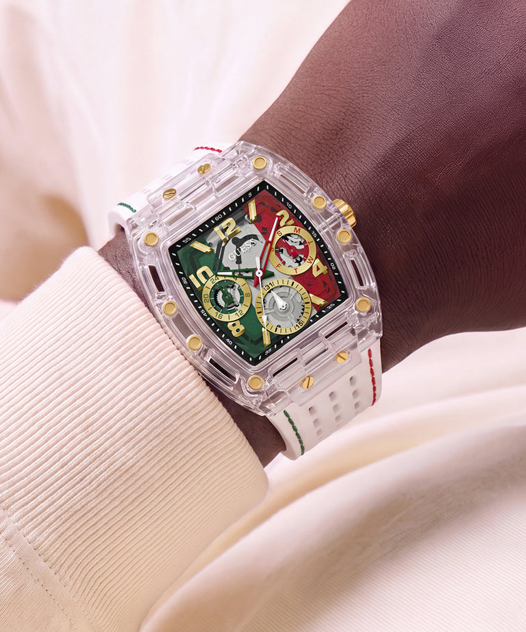 A sports watch with a transparent acrylic case, gold-tone accents, and a green and red dial, shown worn on a wrist with a cream-colored ribbed shirt in the background.