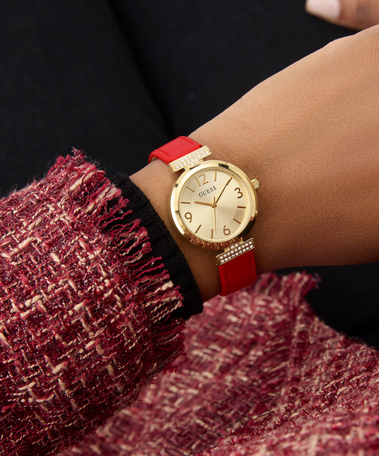 GUESS Ladies Red Gold Tone Analog Watch with a red strap worn on a wrist against a dark background