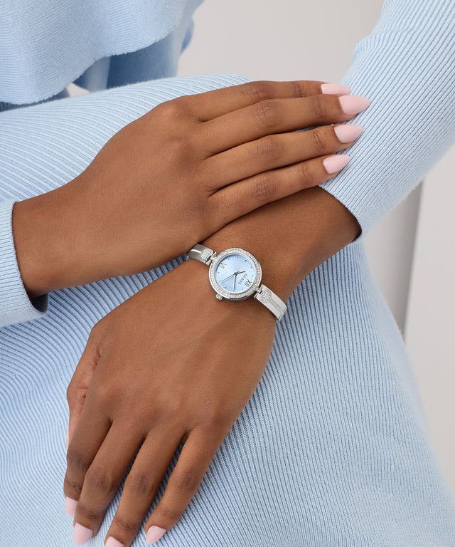 Silver GUESS Ladies Silver Tone Analog Watch on a wrist with a light blue sweater
