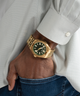  GUESS Mens Gold Tone Analog Watch lifestyle gold watch on wrist hand in pocket