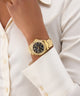 GUESS Ladies Gold Tone Multi-function Watch on a wrist with a white shirt