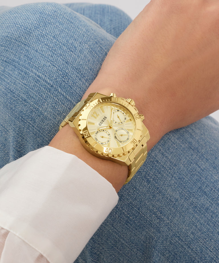 Gold watch on a wrist with a denim background