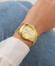 Gold watch on a wrist with a denim background
