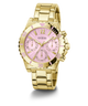 A gold-tone stainless steel wristwatch with a pink sunburst dial, featuring three subdials, gold-tone hour markers, and a matching gold-tone metal link bracelet. The brand name 'GUESS' is printed on the dial.