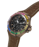 A GUESS chronograph watch with a brown textured fabric strap, a bronze-toned case, and a black dial. The octagonal bezel is decorated with colorful gemstones in blue, green, yellow, pink, and white. lifestyle