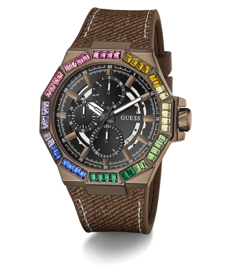 A GUESS wristwatch with a brown textured strap, a bronze-toned case, and a black dial surrounded by a vibrant rainbow bezel of colored gemstones, shown on a white background with a soft shadow.