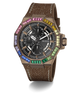A GUESS wristwatch with a brown textured strap, a bronze-toned case, and a black dial surrounded by a vibrant rainbow bezel of colored gemstones, shown on a white background with a soft shadow.