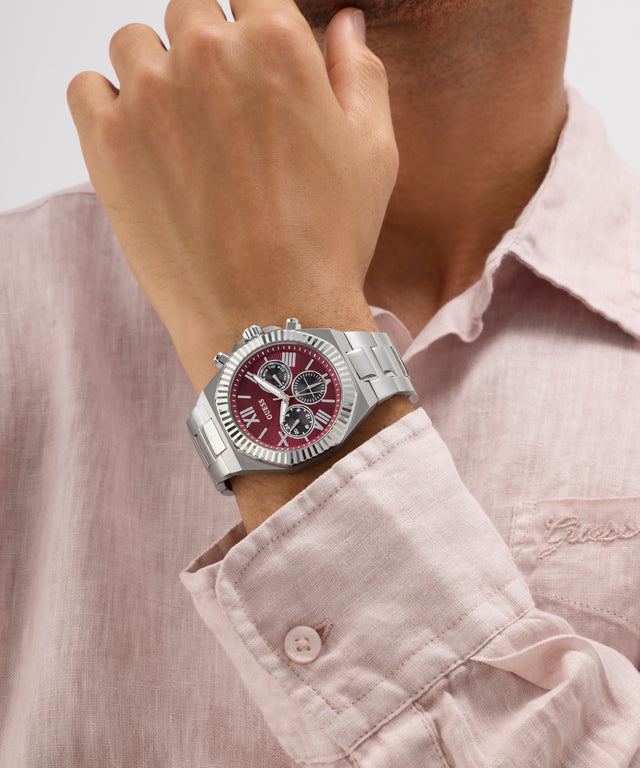 Person wearing a silver GUESS Mens Equity Silver Tone Analog Watch with a red face on a light pink shirt.