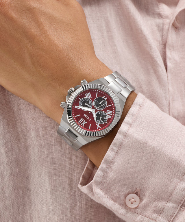 GUESS Mens Equity Silver Tone Analog Watch with a red face on a wrist, wearing a light pink shirt.