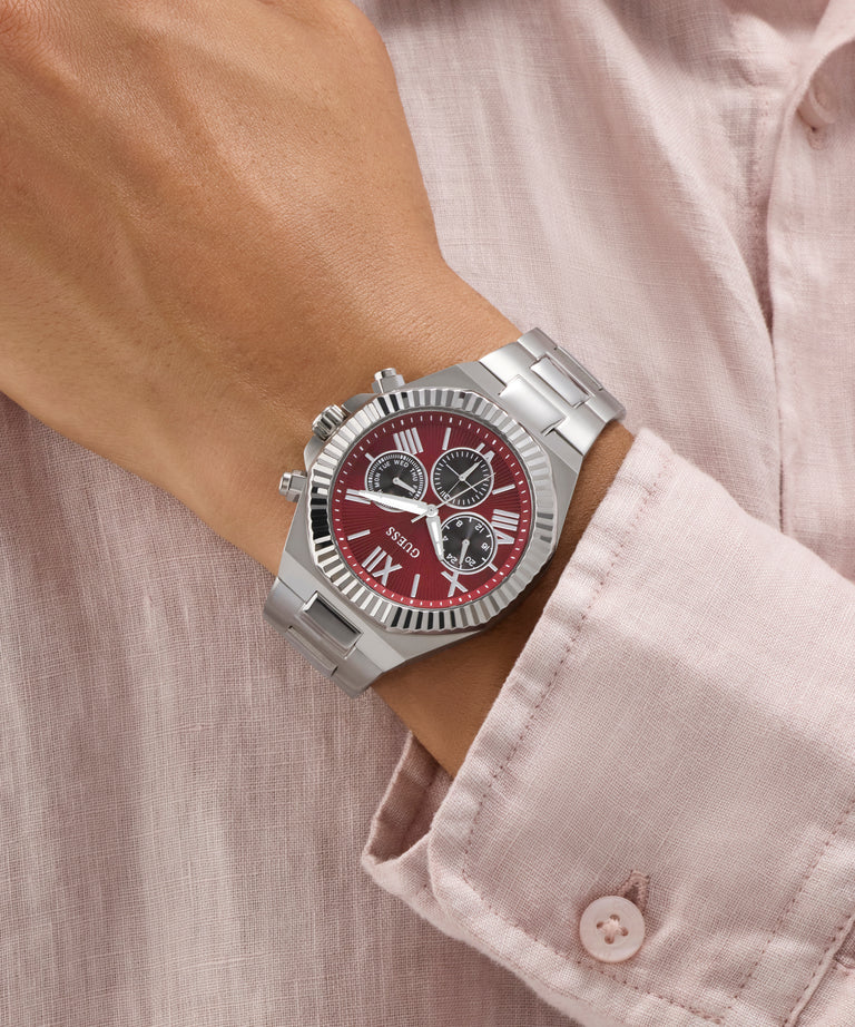 GUESS Mens Equity Silver Tone Analog Watch with a red face on a wrist, wearing a light pink shirt.