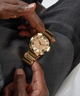 GW0727G1 GUESS Mens Gold Tone Analog Watch lifestyle hand holding watch