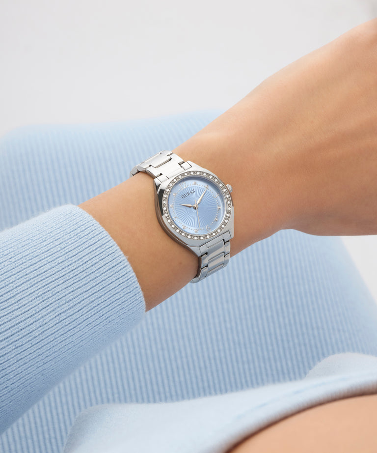 GUESS Ladies Silver Tone Analog Watch on a wrist with a light blue background