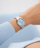 GUESS Ladies Silver Tone Analog Watch on a wrist with a light blue background