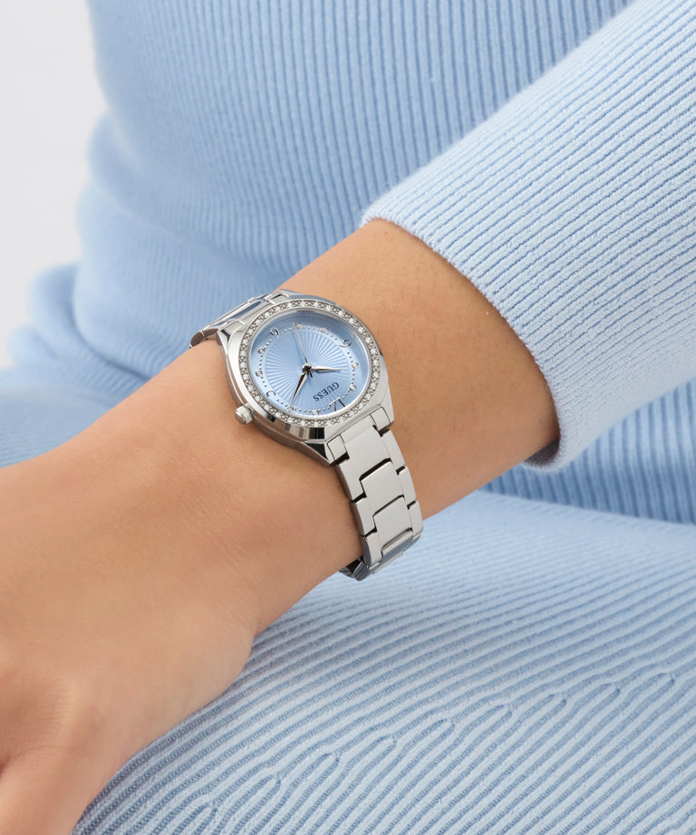 GUESS Ladies Silver Tone Analog Watch on a wrist with a light blue background