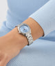 GUESS Ladies Silver Tone Analog Watch on a wrist with a light blue background