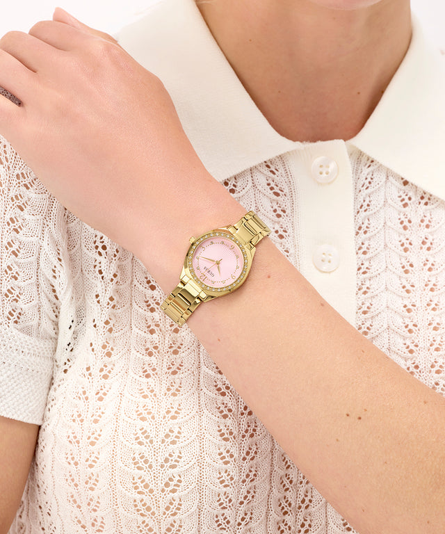 GUESS Ladies Gold Tone Analog Watch on a wrist with a white lace top