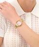 GUESS Ladies Gold Tone Analog Watch on a wrist with a white lace top