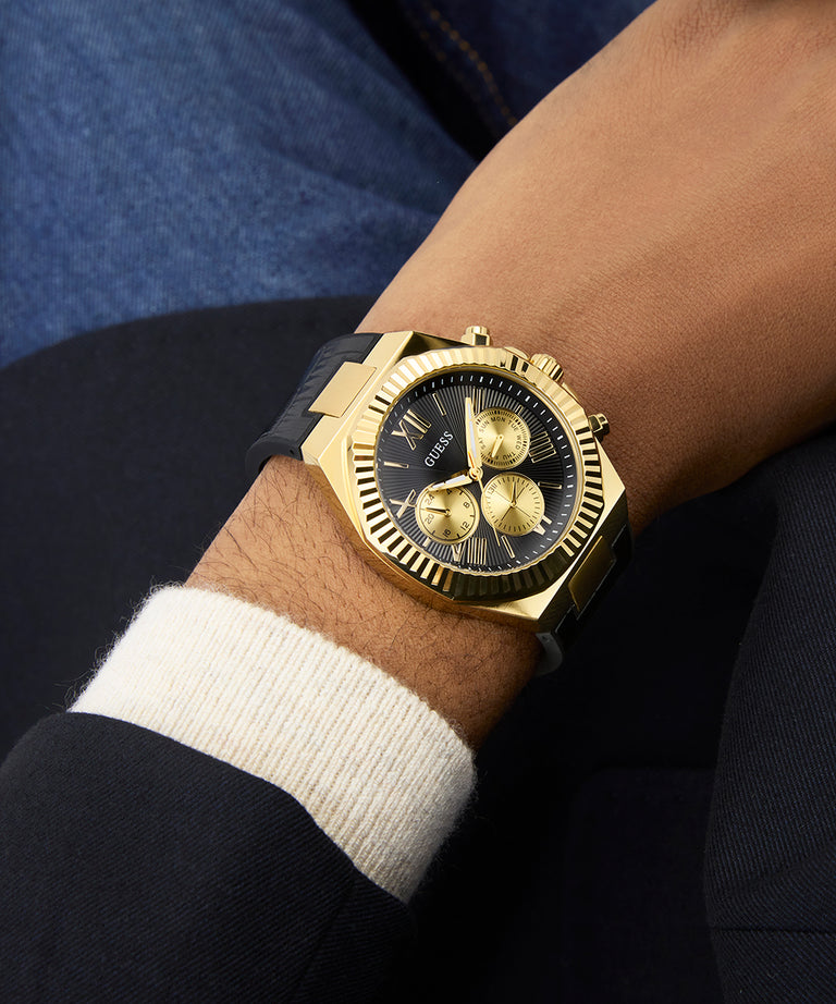 GUESS Mens Black Gold Tone Multi-function Watch on a wrist with a dark background