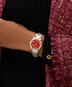 GUESS Ladies 2-Tone Analog Watch with a red face on a wrist, wearing a black sweater and maroon cardigan.