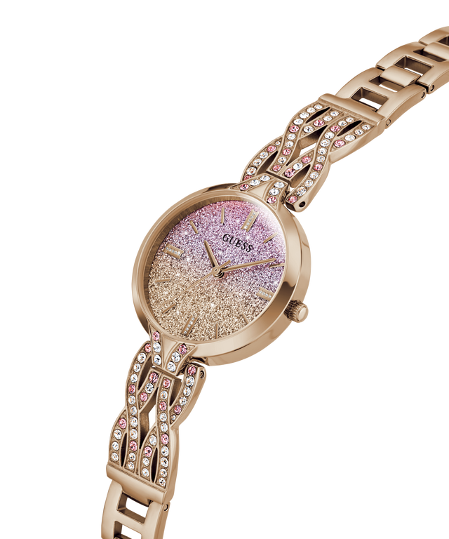 A rose gold Guess watch with a glittery pink and gold dial and a matching rose gold link bracelet embellished with rhinestones, shown on a plain white background. lifestyle