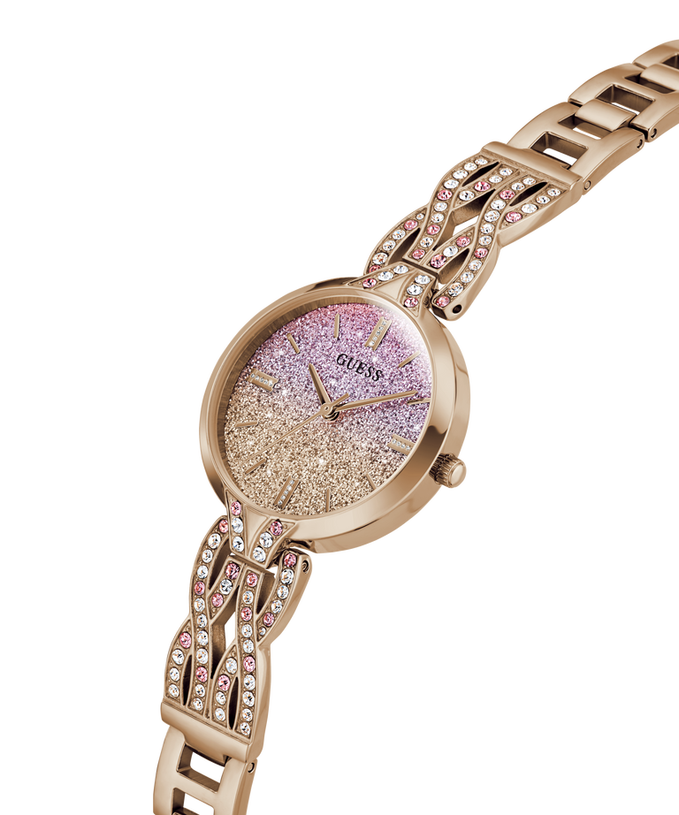A rose gold Guess watch with a glittery pink and gold dial and a matching rose gold link bracelet embellished with rhinestones, shown on a plain white background. lifestyle