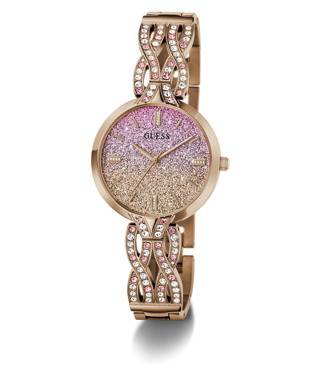 A Guess women's watch with a rose gold-tone metal bracelet and case, featuring a glittery pink-to-gold gradient dial and crystal-studded decorative links on the bracelet.