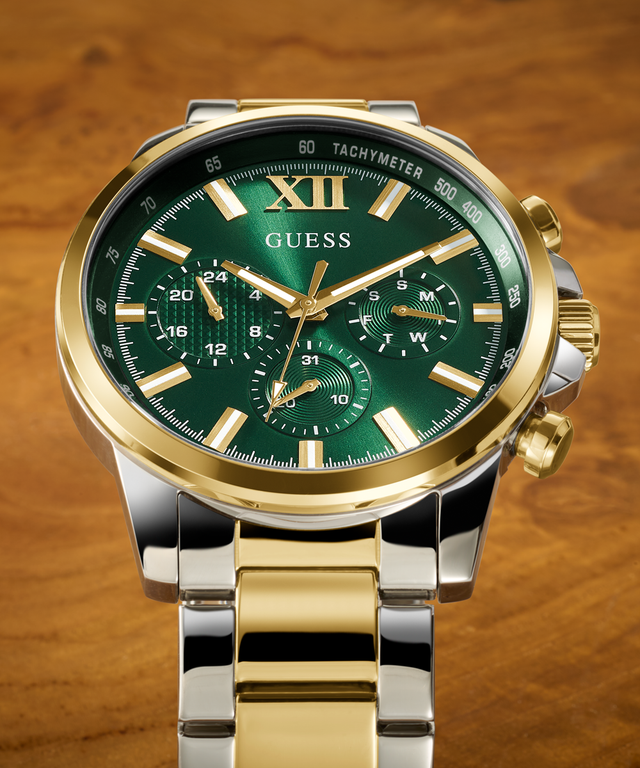 close up of mens guess watch with silver and gold band and green dial