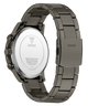 A close-up studio shot of a GUESS watch showing the back of the case and the metal link band. The watch has a dark gunmetal gray stainless steel case and band, with a polished silver-toned circular back plate.