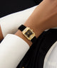 GUESS Ladies Black Gold Tone Analog Watch on a wrist