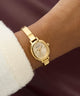 Gold Guess watch on a wrist with a blurred background GW0924L2