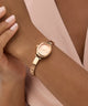 Rose gold GUESS Ladies Rose Gold Tone Analog Watch on a wrist with a neutral background