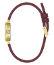 A minimalist watch with a slim burgundy leather strap and a gold-tone rectangular case, shown from a side profile view against a solid white background.