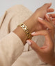 Gold chain bracelet on a wrist GUESS Ladies Gold Tone Analog Watch with a neutral background