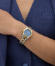 GUESS Ladies 2-Tone Analog Watch on a wrist with a blue background
