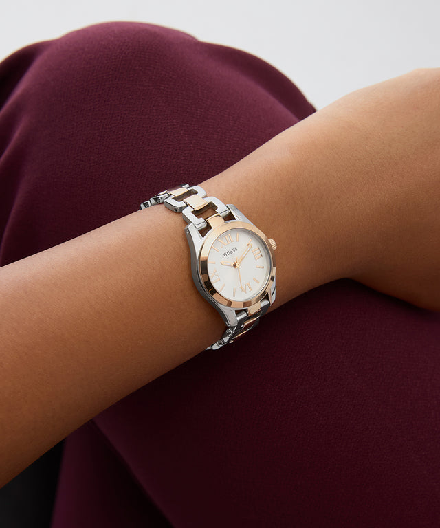 GUESS Ladies 2-Tone Analog Watch on a wrist with a maroon fabric background