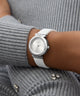 GUESS Ladies White Silver Tone Analog Watch with silver case on a person wearing a gray sweater.